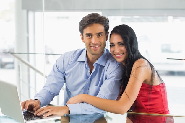 Portrait of couple using laptop in cafe