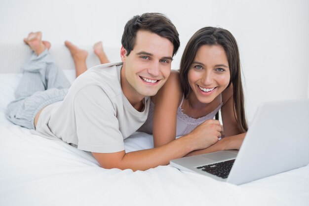 Portrait of a couple using a laptop lying in bed