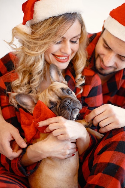 Photo portrait of a couple wearing christmas plaid red pajamas with dog