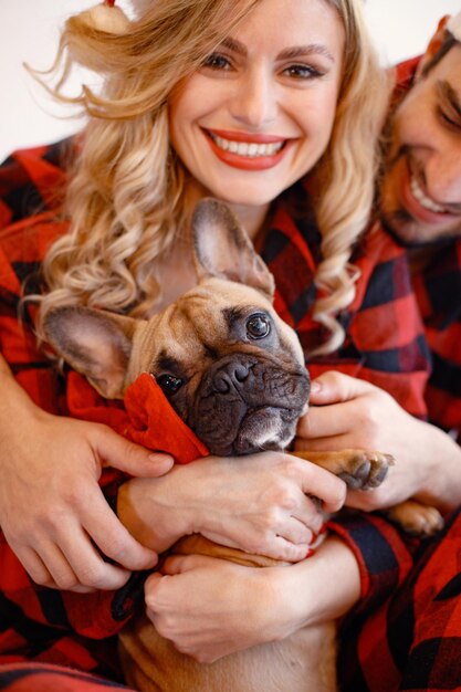 Portrait of a couple wearing christmas plaid red pajamas with dog