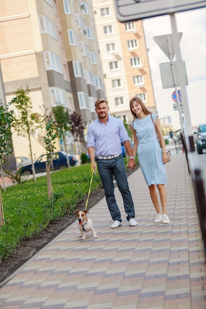 Portrait of couple with dog walking on footpath