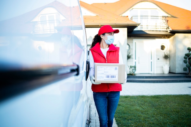 Portrait of courier holding parcels by her van ready to deliver during corona virus pandemic