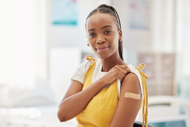 Photo portrait covid or vaccine and a black woman with a plaster on arm sitting in a hospital medical insurance or healthcare and a female in a clinic with a bandaid on shoulder for corona vaccination