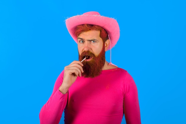 Portrait of cowboy with lollipop man wearing cowboy hat american bandit western man with hat pink