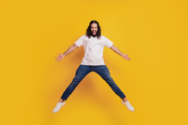 Portrait of crazy active brunet guy jump have fun on yellow background