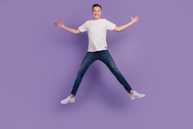 Portrait of crazy dreamy positive guy jump have fun on purple background