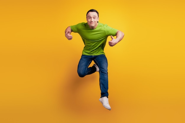 Portrait of crazy energetic guy jump sport concept on yellow wall