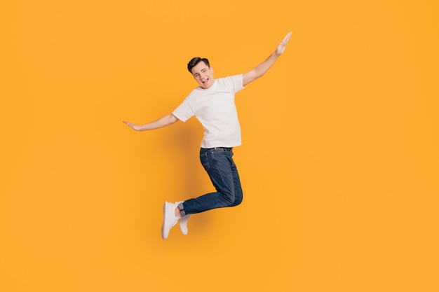 Photo portrait of crazy inspired guy jump make plan figure hands wings on yellow background