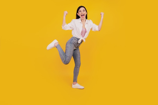 Portrait of crazy pretty girl raise fists open mouth on yellow background