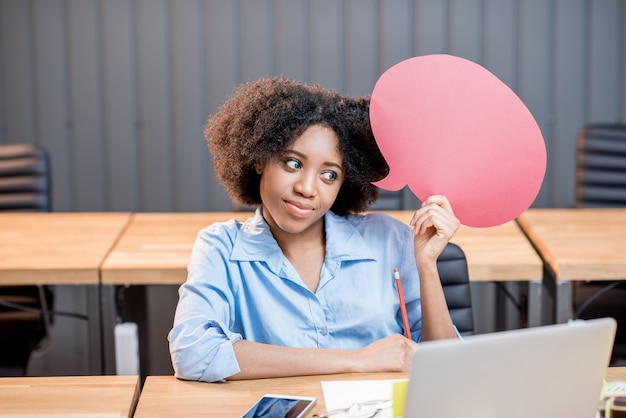 Portrait of creative african ethnicity businesswoman sitting with thought bubble at the office