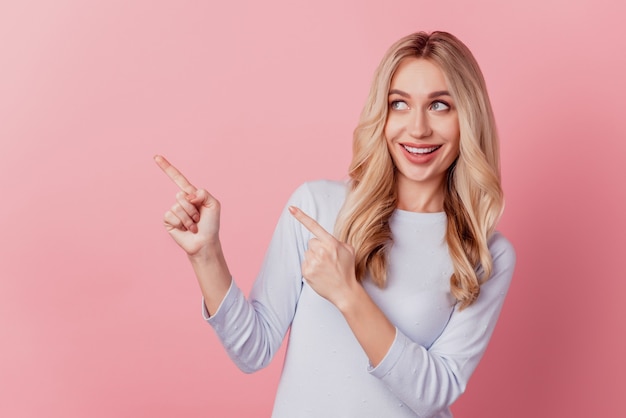 Portrait of curious adorable pretty lady indicate finger empty space look away on pink background