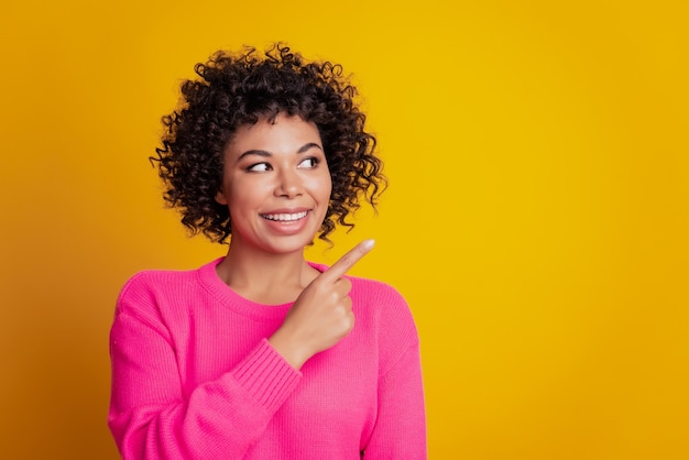 Portrait of curious dreamy girl point finger copyspace isolated over yellow color background