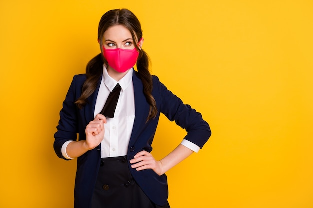 portrait of curious minded schoolgirl wearing pink mask pulling tie flirt