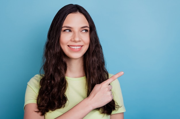 Portrait of curious pretty positive lady direct forefinger blank space look side on blue background