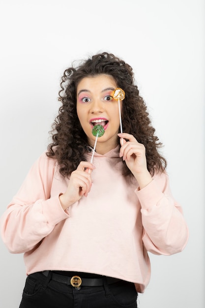 Portrait of curly brunette woman with colorful lollipops posing.