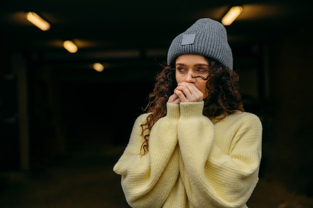 A portrait of a curly hair woman wearing a hat and sweater