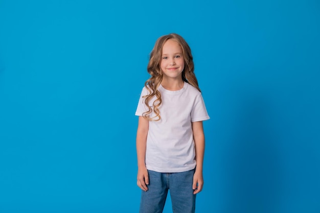 portrait of a curly-haired girl in jeans and a white T-shirt on a blue background