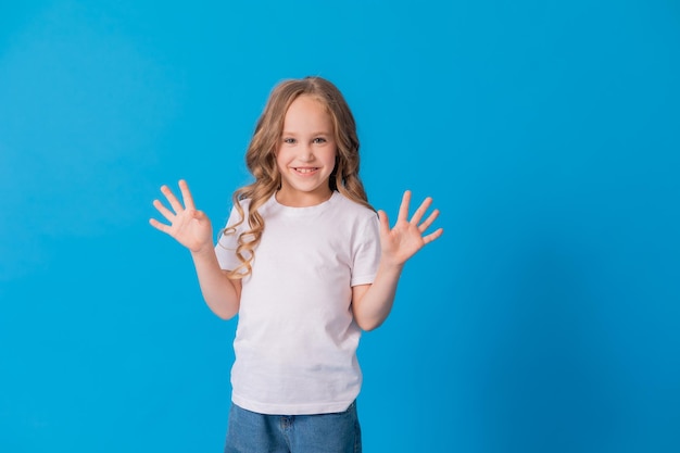 portrait of a curly-haired girl in jeans and a white T-shirt on a blue background