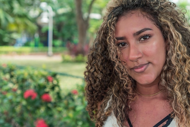 Portrait of curly-haired Latin woman on the park