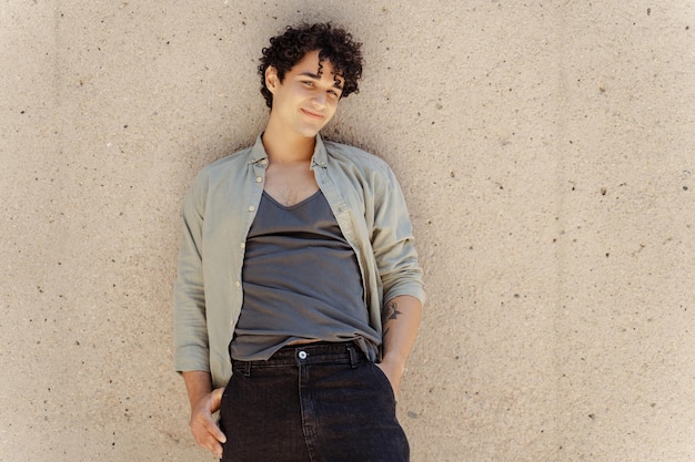 Portrait of curly teen man wearing casual clothing standing on the street