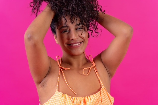 Portrait of a curlyhaired woman in summer clothes on a pink background studio shot