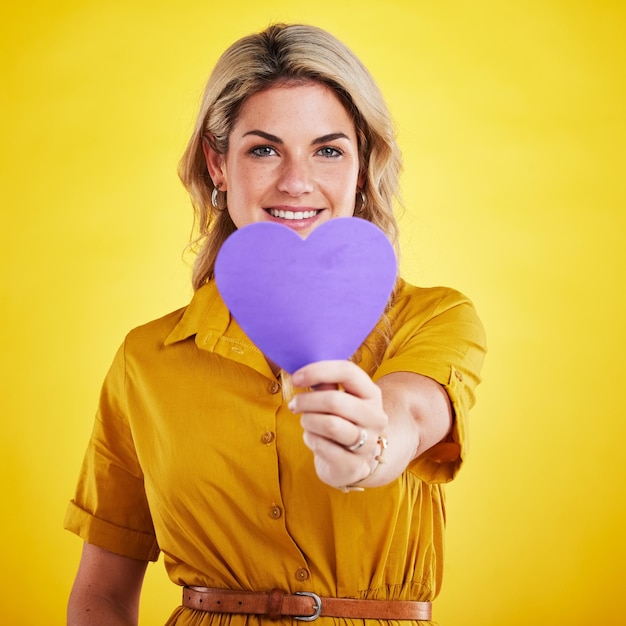 Portrait cut out heart and woman with support smile and wellness against a studio background Face female person and model with a symbol for love paper and sign with happiness romance and loving