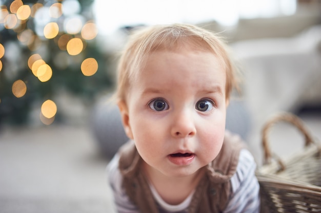 Portrait of a cute 1 year old baby boy sitting on the floor.