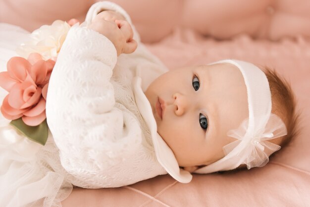 Portrait of a cute 6-month-old baby, a newborn girl lying in a baby crib