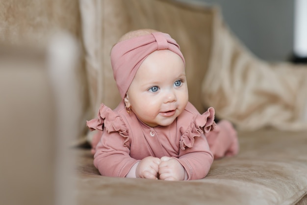 Portrait of a cute 6-month-old baby, a newborn girl lying in a bed.