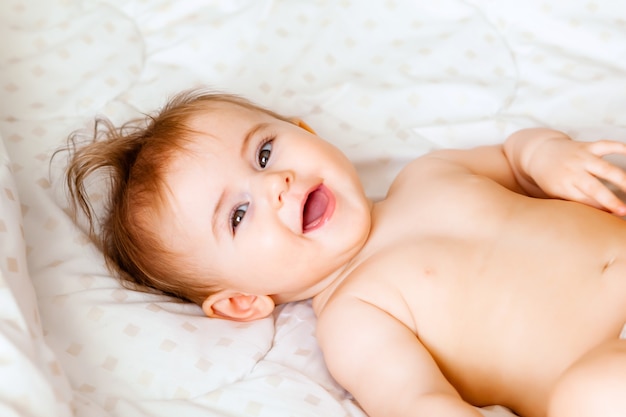 毛布の上に横たわっているかわいい6ヶ月の赤ちゃんの肖像画。小さな幸せな赤ちゃん