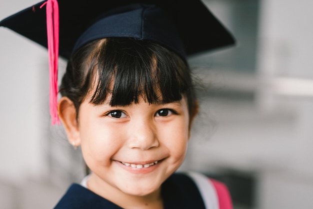 Portrait of a cute asian graduated schoolgirl with graduation\
gown in school