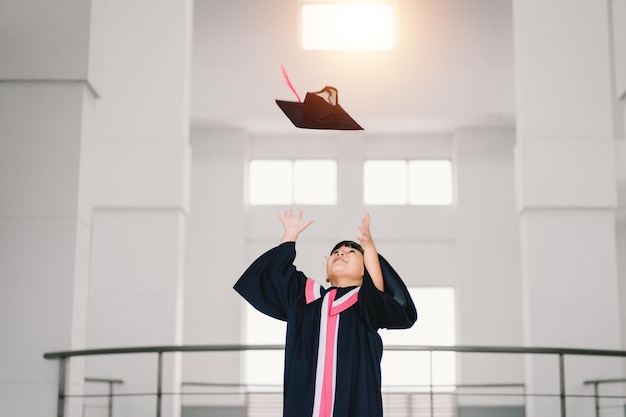 Portrait of a cute asian graduated schoolgirl with graduation\
gown in school