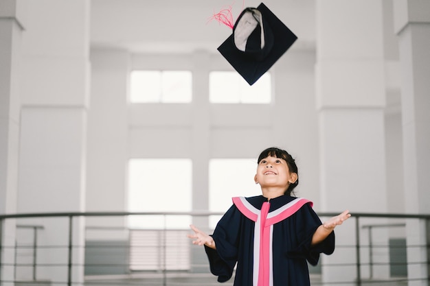 Ritratto di una studentessa laureata asiatica carina con abito di laurea a scuola