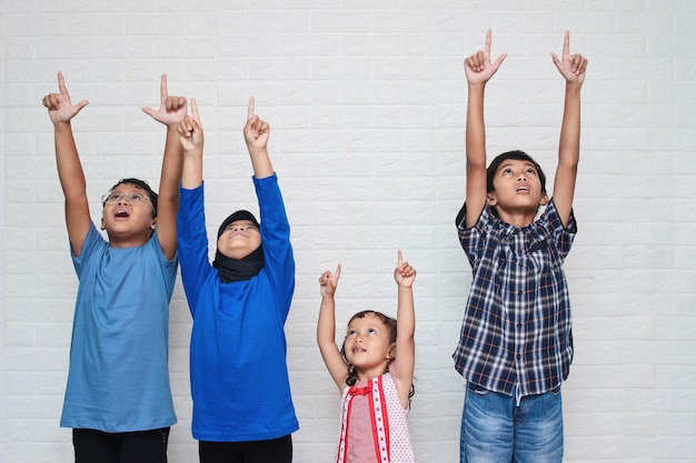 Portrait of cute Asian little kids in casual clothes looking and pointing up