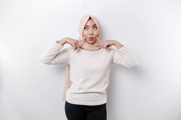 A portrait of a cute Asian Muslim woman wearing a headscarf and feeling excited and isolated by a white background