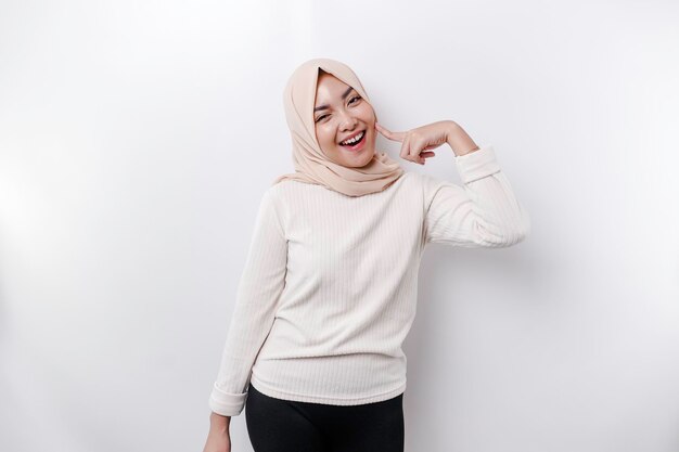 A portrait of a cute Asian Muslim woman wearing a headscarf and feeling excited and isolated by a white background