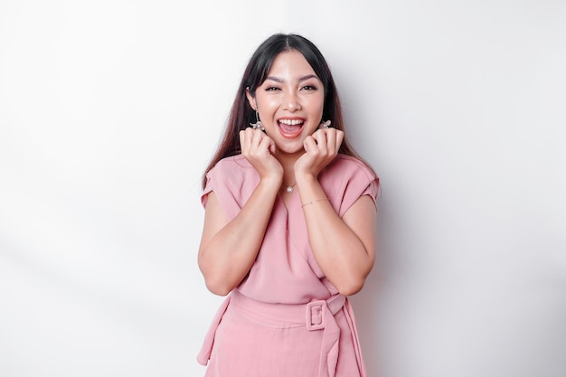 A portrait of a cute Asian woman dressed in pink and feeling excited and isolated by a white background
