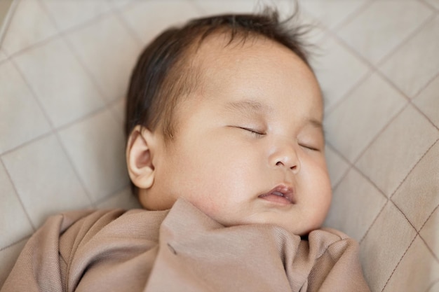 Portrait of cute baby boy sleeping on his bed