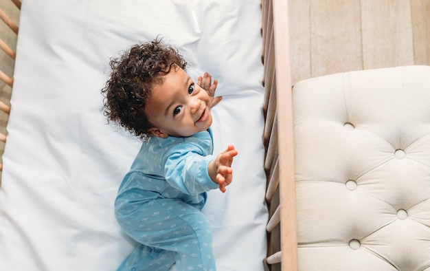 portrait of cute baby boy standing in crib at home