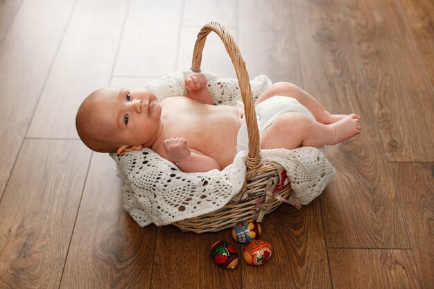 Portrait a cute baby boy  in wicker basket easter.  little newborn baby in wicker basket on wooden wall. smiling child and easter eggs