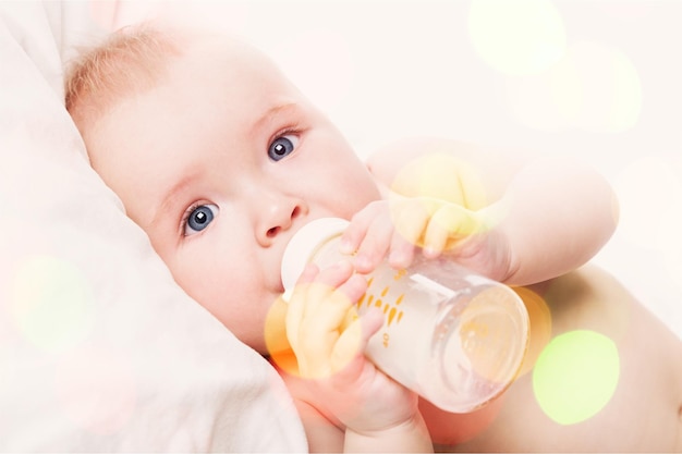 Portrait of cute baby boy with milk on  background