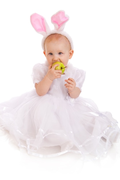 Portrait of a cute baby dressed in Easter bunny ears with a green apple isolated on the white background