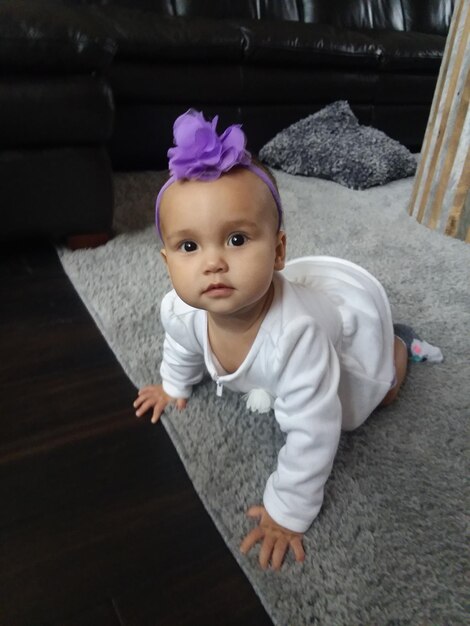 Photo portrait of cute baby girl crawling on rug at home