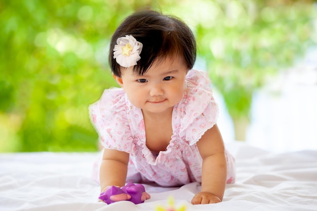 Portrait of cute baby girl lying on bed against window at home