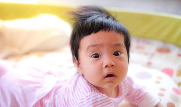 Photo portrait of cute baby girl lying on bed at home