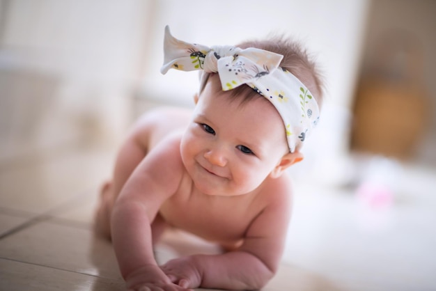 Portrait of cute baby girl lying on tiled floor