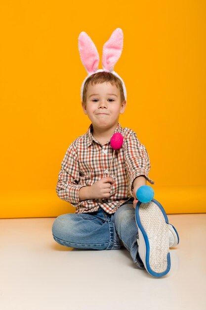 Portrait of cute baby girl sitting against yellow background