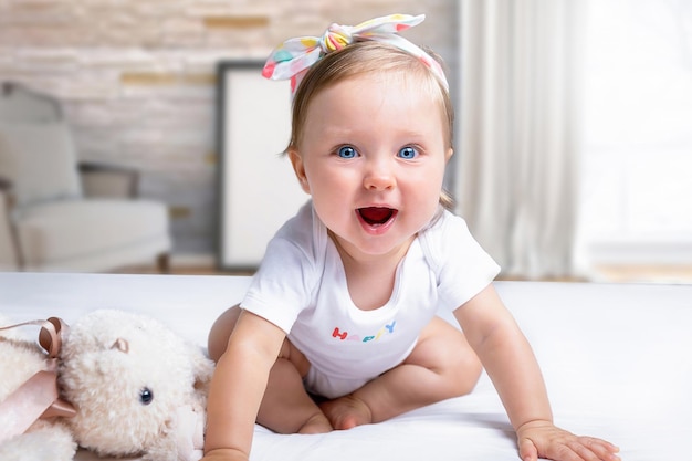 Photo portrait of cute baby girl sitting on bed at home