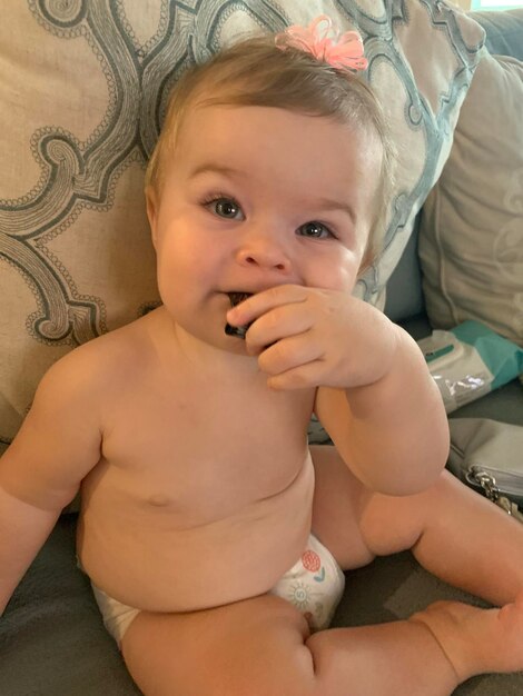 Photo portrait of cute baby girl sitting on bed