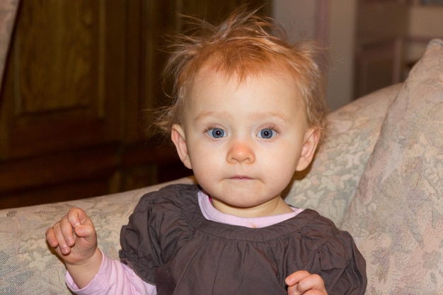 Photo portrait of cute baby girl sitting at home